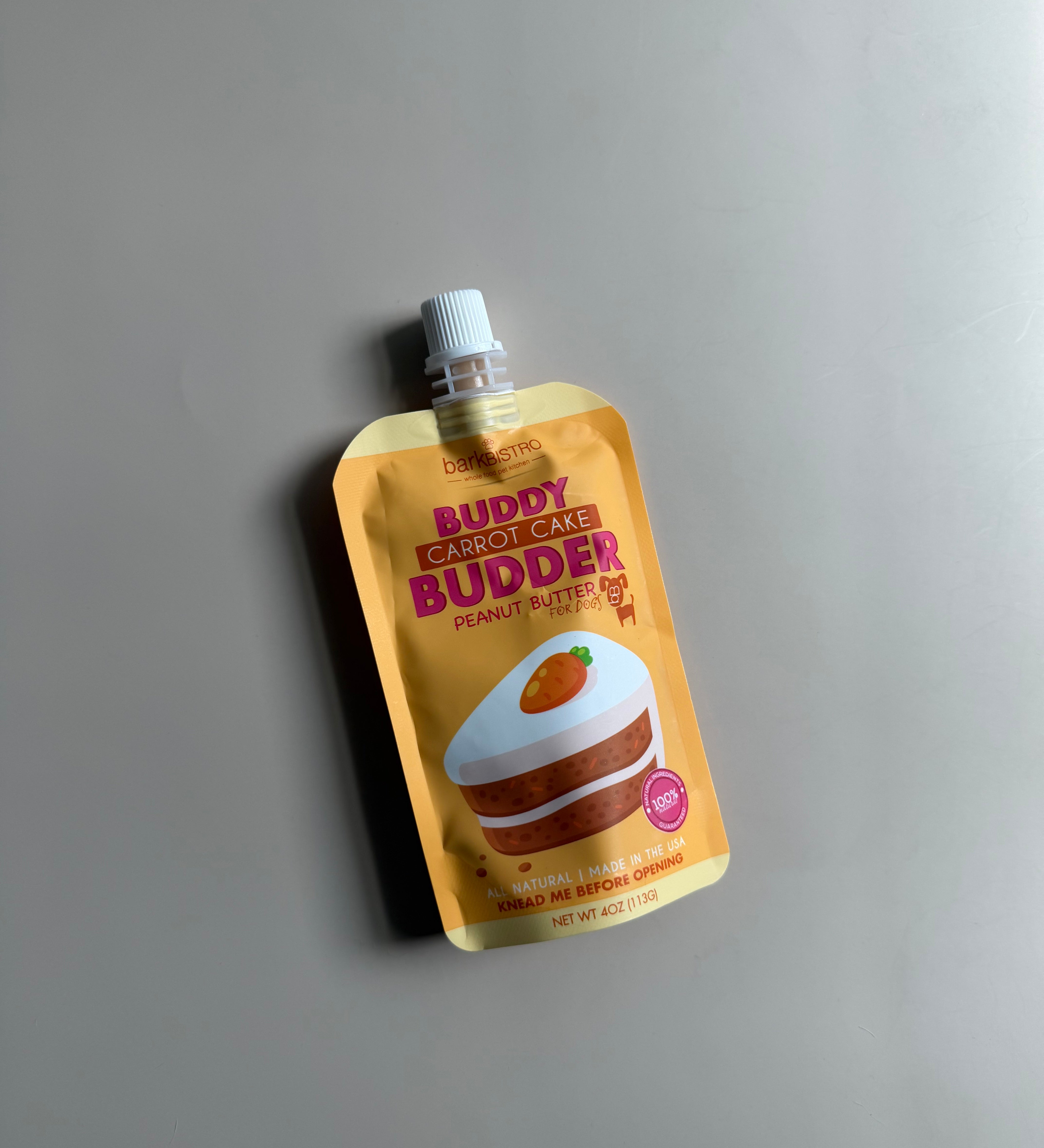 peanut butter pouch for dogs in a carrot cake flavor in an orange and yellow pouch with a carrot cake design
