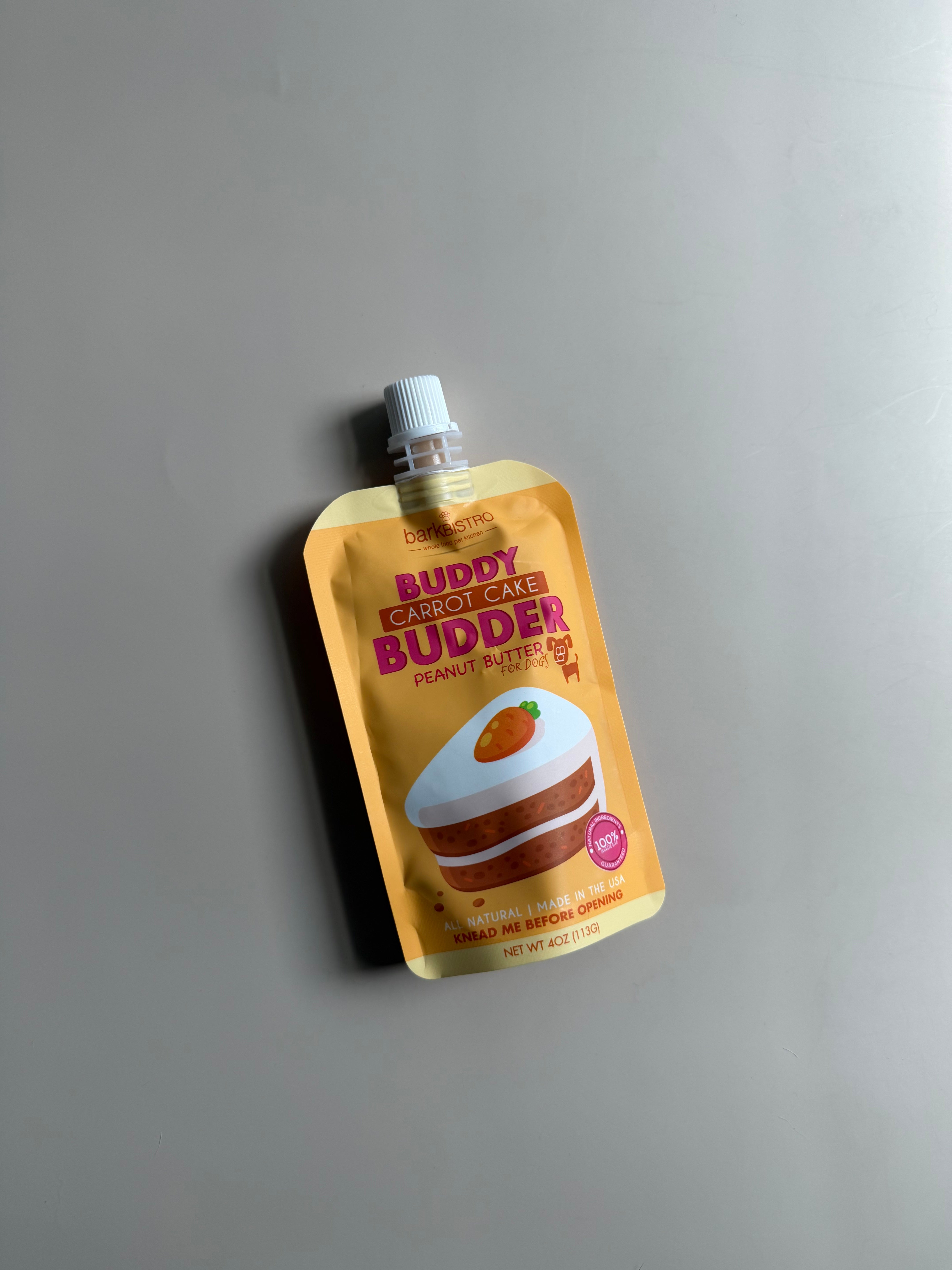 peanut butter pouch for dogs in a carrot cake flavor in an orange and yellow pouch with a carrot cake design