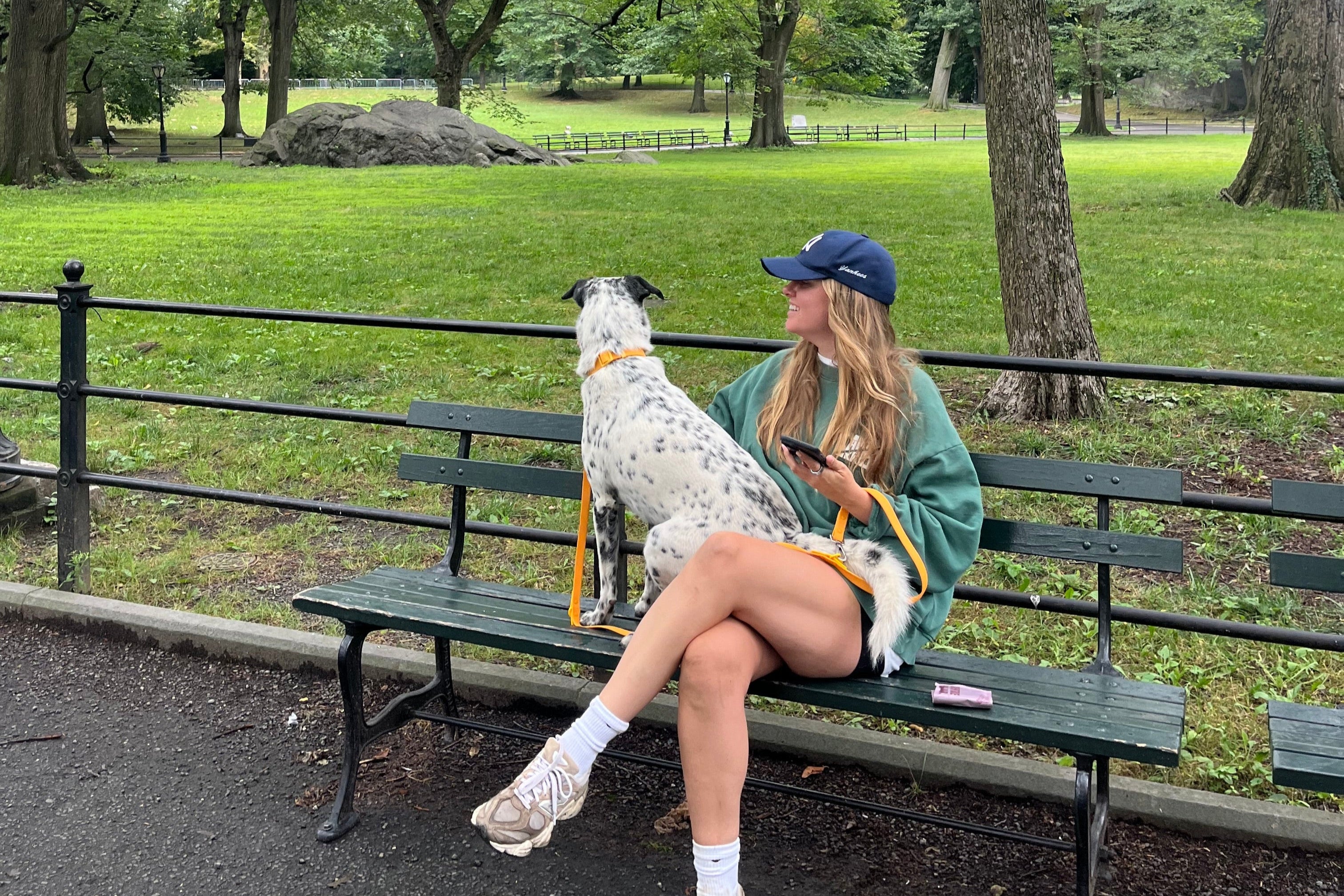 Woman sitting on a bench in a park with her dog enjoying their morning.